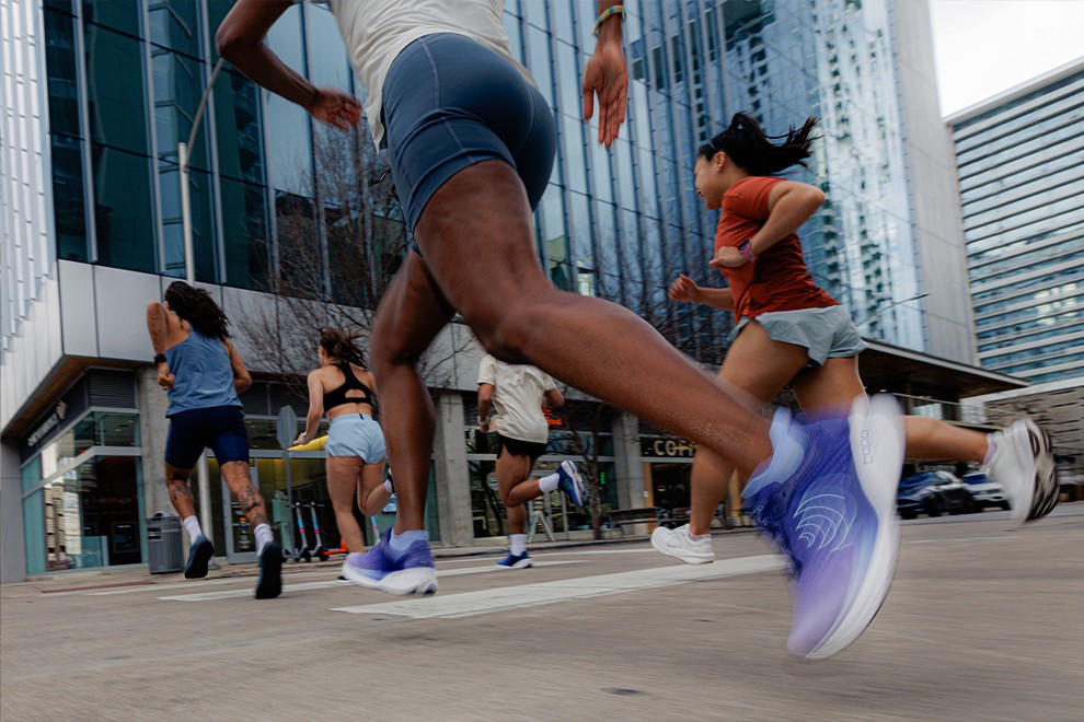 A group of runners wearing comfortable running shoes with wide toe box jogging through a modern city street.
